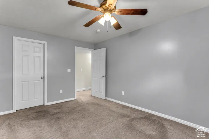 Neutral wall paint, plush carpet flooring, ceiling fan with light, and white paneled doors