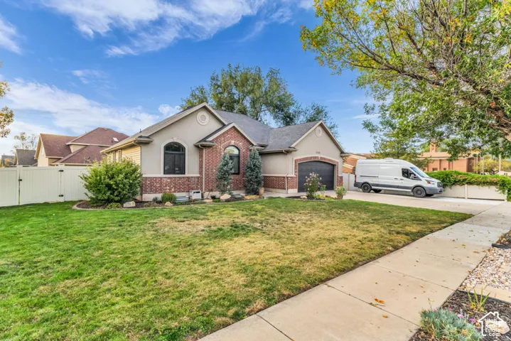 Stucco and brick exterior with arched windows, an integrated garage, and a concrete driveway