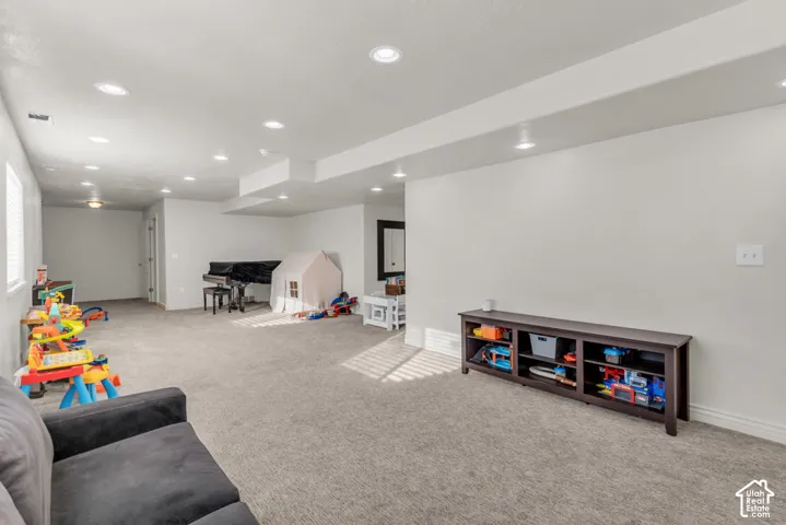 Spacious room featuring neutral carpeting, recessed lighting, and a white color palette