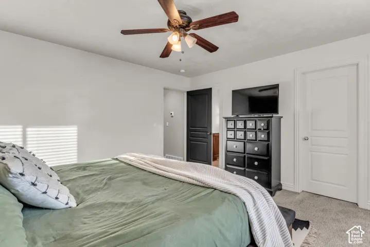 Carpeted room featuring a ceiling fan with integrated lighting, white walls, and white trim
