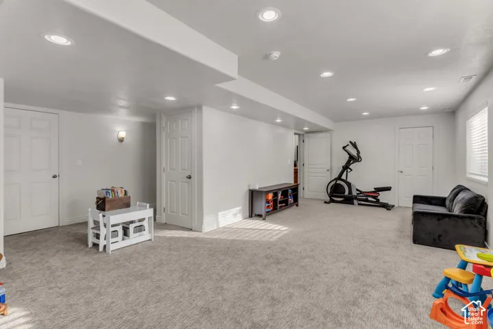 Recessed lighting, wall sconce, two panel doors, and neutral carpeting