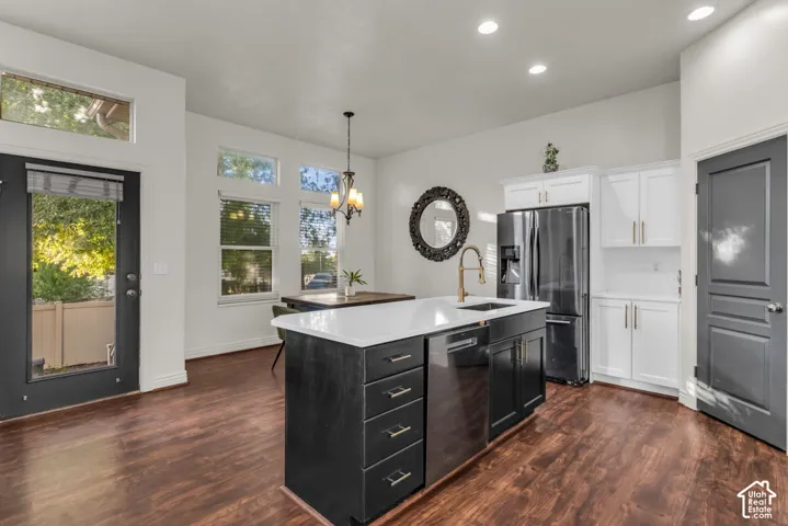 Kitchen featuring a large island with sink, stainless steel appliances, dark wood-finish flooring, and white cabinetry