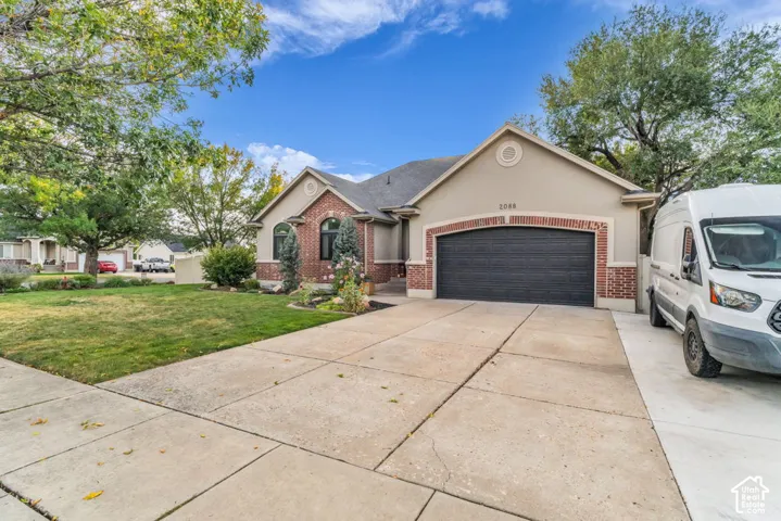 Stucco exterior with brick accents, arched windows, an attached garage, and a concrete driveway