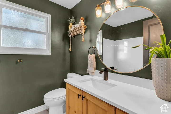 White vanity countertop with an integrated sink, bronze-finish faucet, and a circular framed mirror with an overhead light fixture