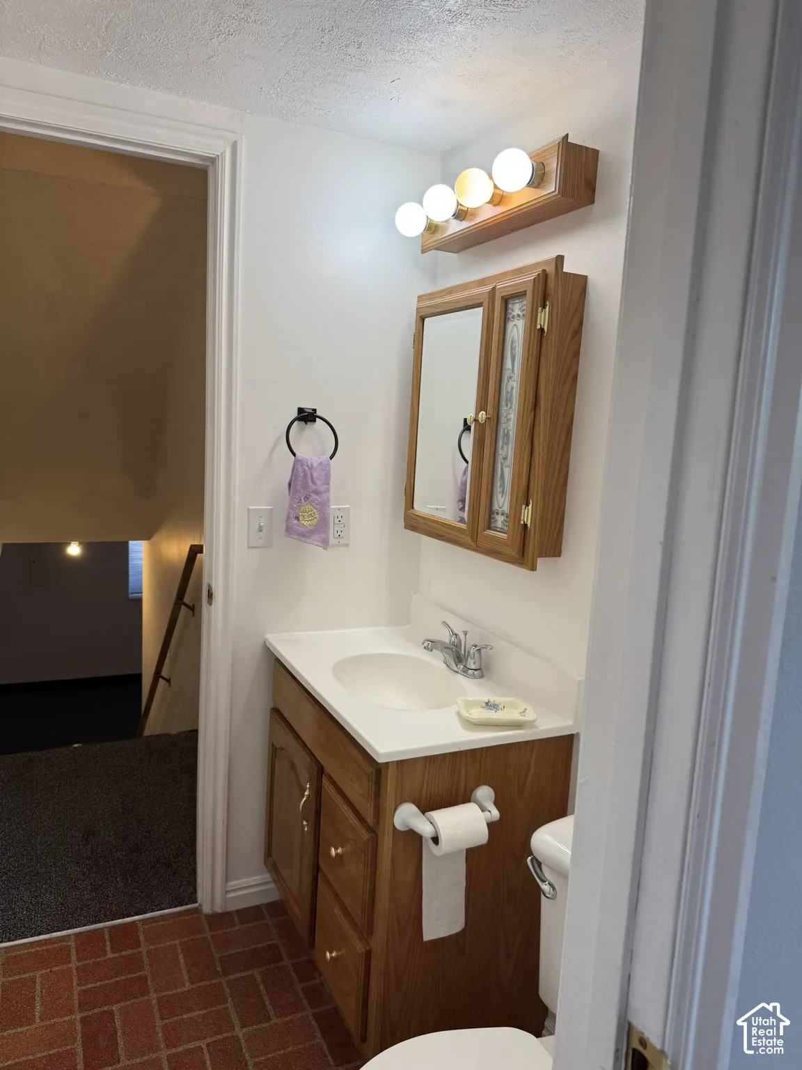 Vanity with a white countertop and integrated sink, wood-finish cabinetry, and a mirrored medicine cabinet