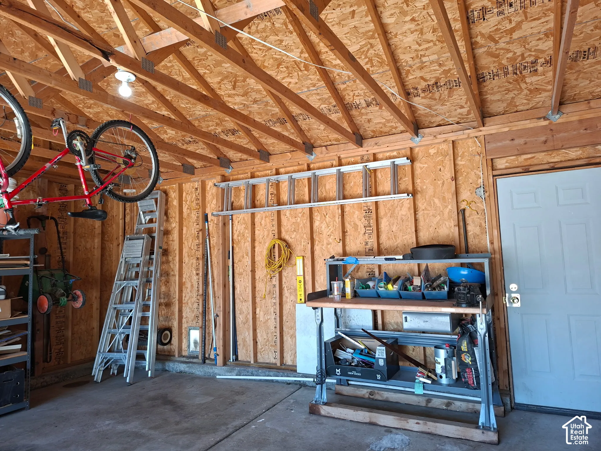 Exposed wood beam ceiling, wood-paneled walls, concrete flooring, and a paneled entry door