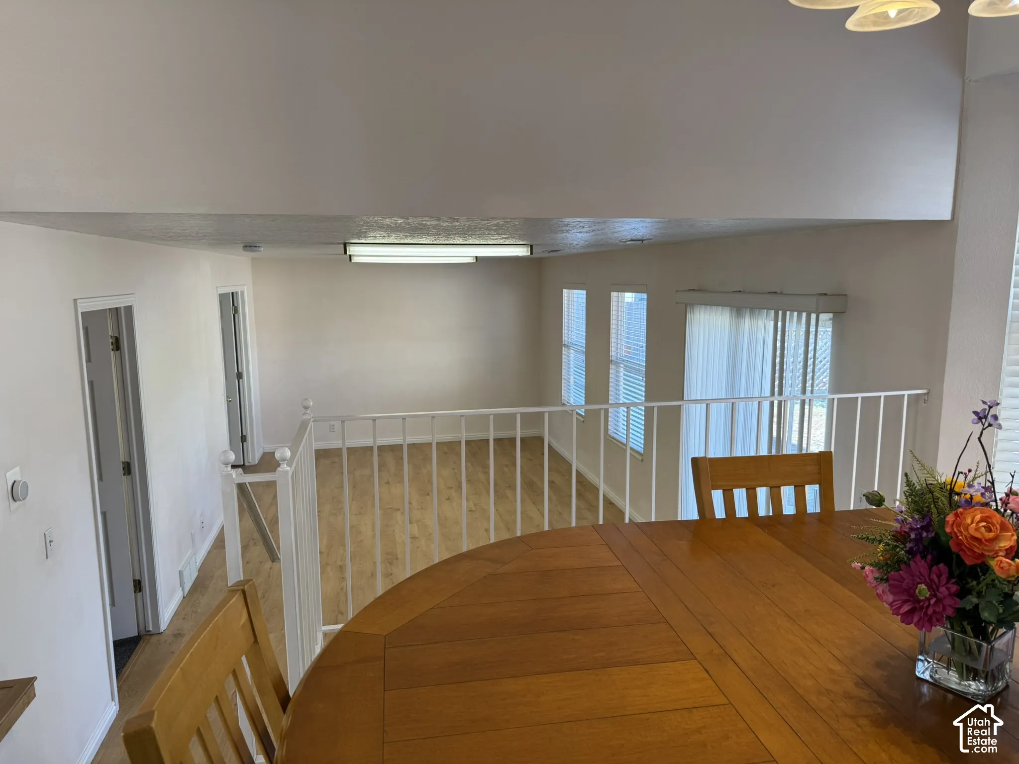 Open-concept living space with wood-finish flooring, white railing, and multiple windows