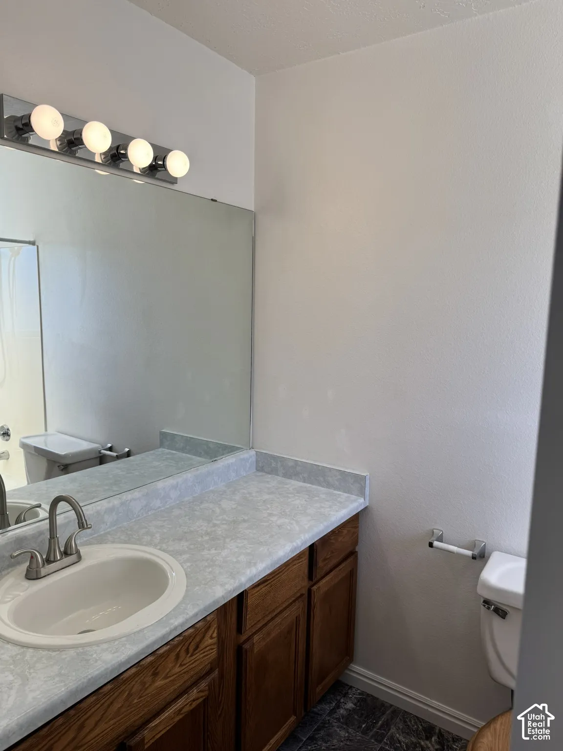Vanity with wood-finish cabinetry, integrated sink, and light-colored countertop
