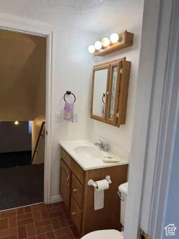 Vanity with a white countertop and integrated sink, wood-finish cabinetry, and a mirrored medicine cabinet