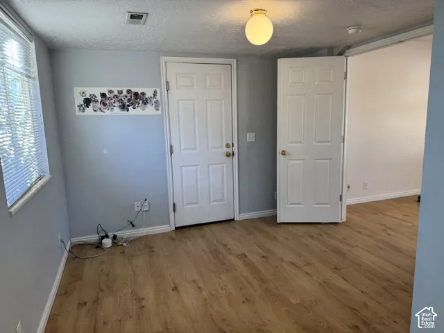 Wood-finish flooring throughout, white interior doors, and a window with horizontal blinds