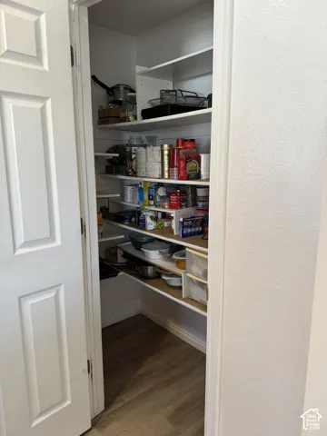 Walk-in pantry with wood-finish flooring and extensive shelving
