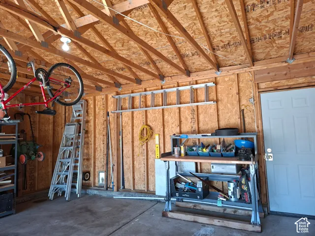Exposed wood beam ceiling, wood-paneled walls, concrete flooring, and a paneled entry door