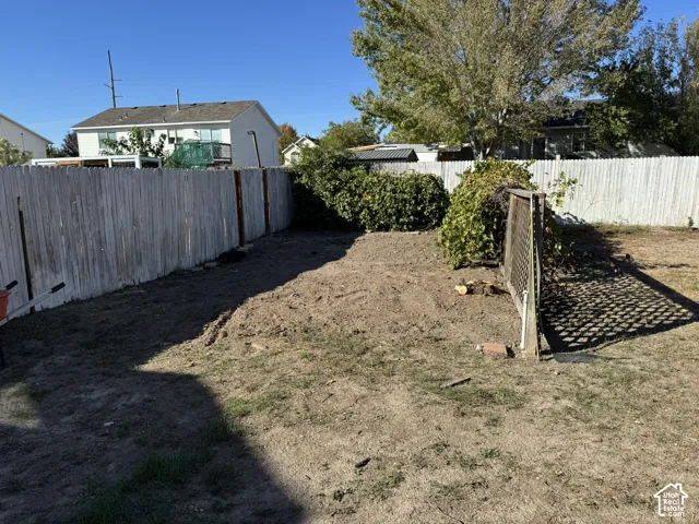 Private backyard space featuring wood panel fencing, established perimeter shrubbery, and a trellised section