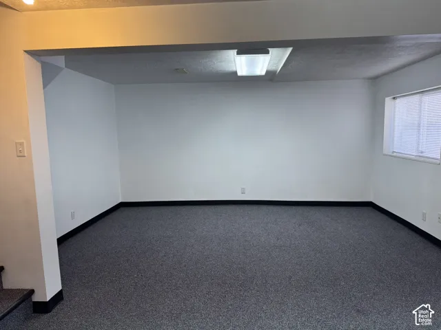 Recessed fluorescent lighting, textured ceiling, light-colored walls, dark baseboards, and window with blinds