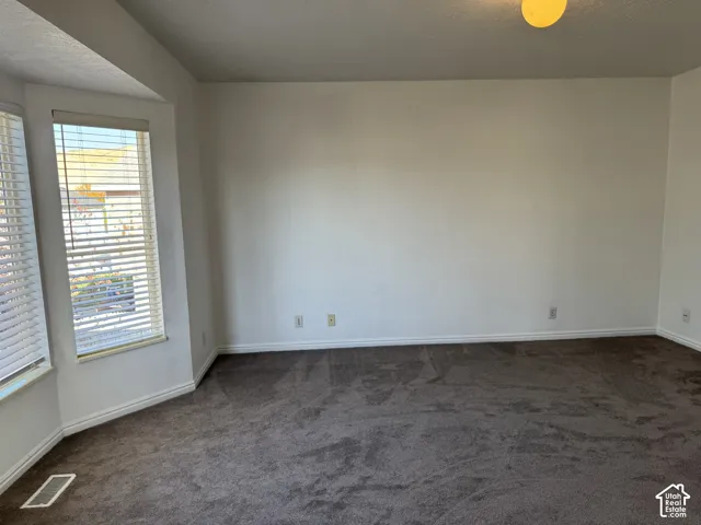 Bay window with horizontal blinds, wall-to-wall carpeting, and white wall paint