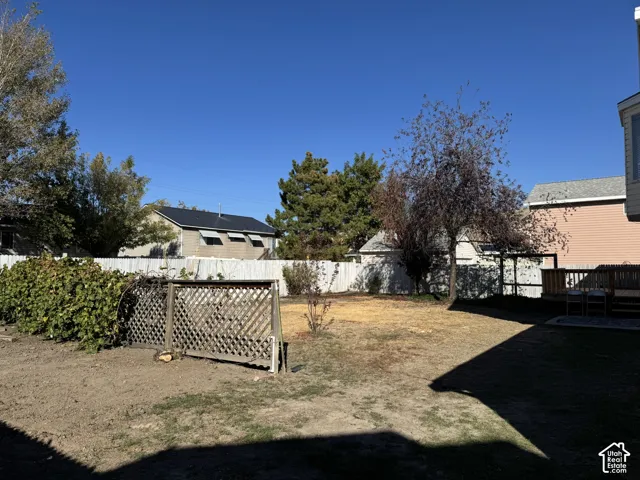 Expansive backyard featuring mature trees, a wooden privacy fence, and a built-in wooden deck