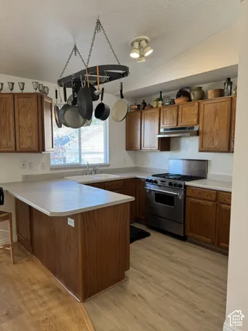 Kitchen featuring wood-finish cabinetry, light-toned countertops, a stainless steel range, and wood-finish flooring