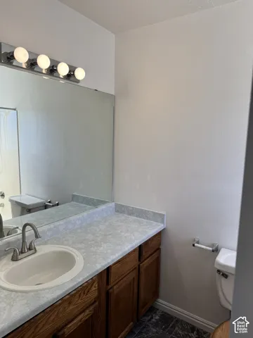 Vanity with wood-finish cabinetry, integrated sink, and light-colored countertop