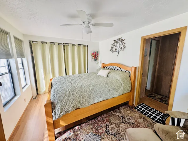 Wood-finish flooring, multiple windows with blinds, and an overhead ceiling fan
