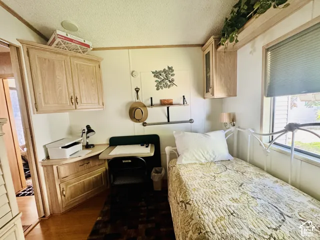 Built-in cabinetry, desk with integrated storage, wood-finish flooring, and window with privacy blinds
