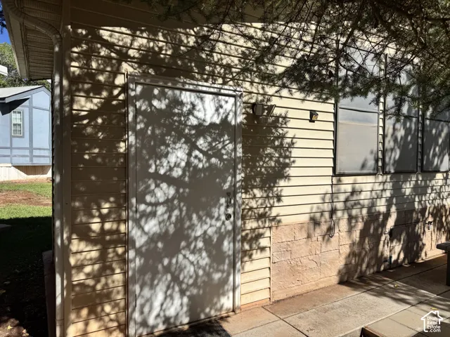 Exterior siding with a stone-look foundation, featuring a solid entry door and translucent windows