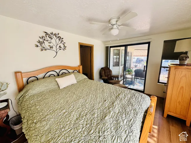 Wood-finish flooring, ceiling fan with integrated lighting, built-in sliding glass door, built-in window, and a wood bed frame