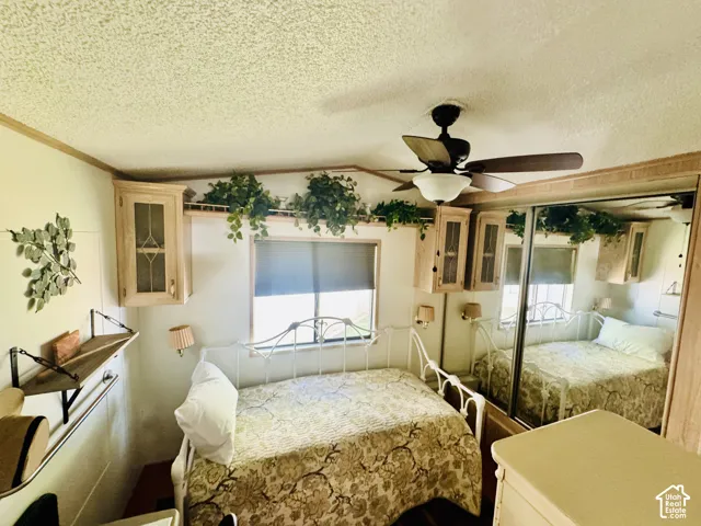 Mirrored closet doors, built-in cabinetry, ceiling fan, and wall-mounted lighting fixtures