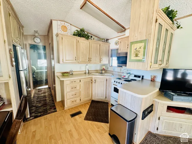 Kitchen featuring wood-finish cabinetry, solid surface countertops, a built-in electric range, and wood-finish flooring