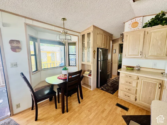 Built-in bay window bench seating, overhead lighting fixture, wood-finish flooring, and light wood cabinetry with glass-front accents