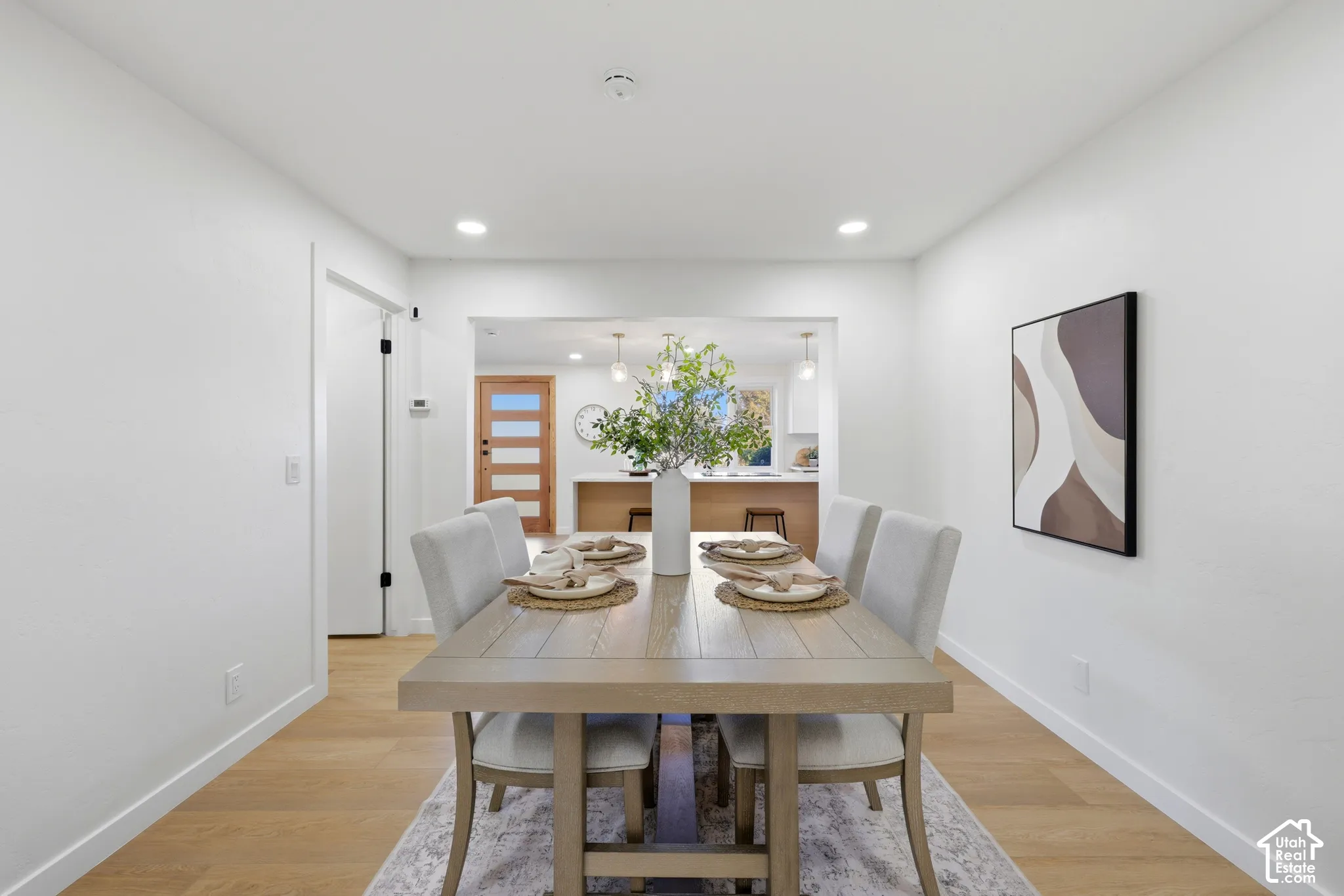 Recessed lighting illuminates the space, featuring wood-finish flooring and a white color palette