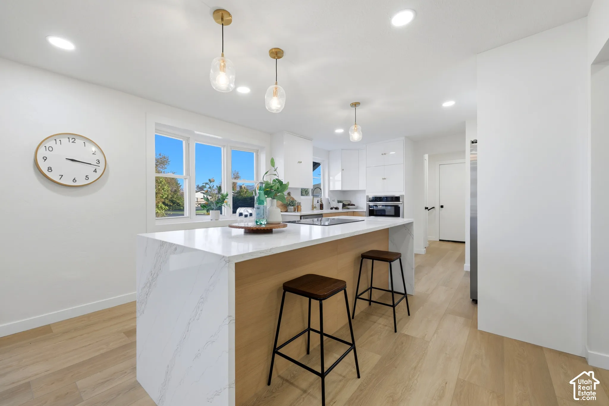 Kitchen featuring a waterfall island with stone countertop, wood-finish flooring, recessed lighting, pendant lighting, and white cabinetry