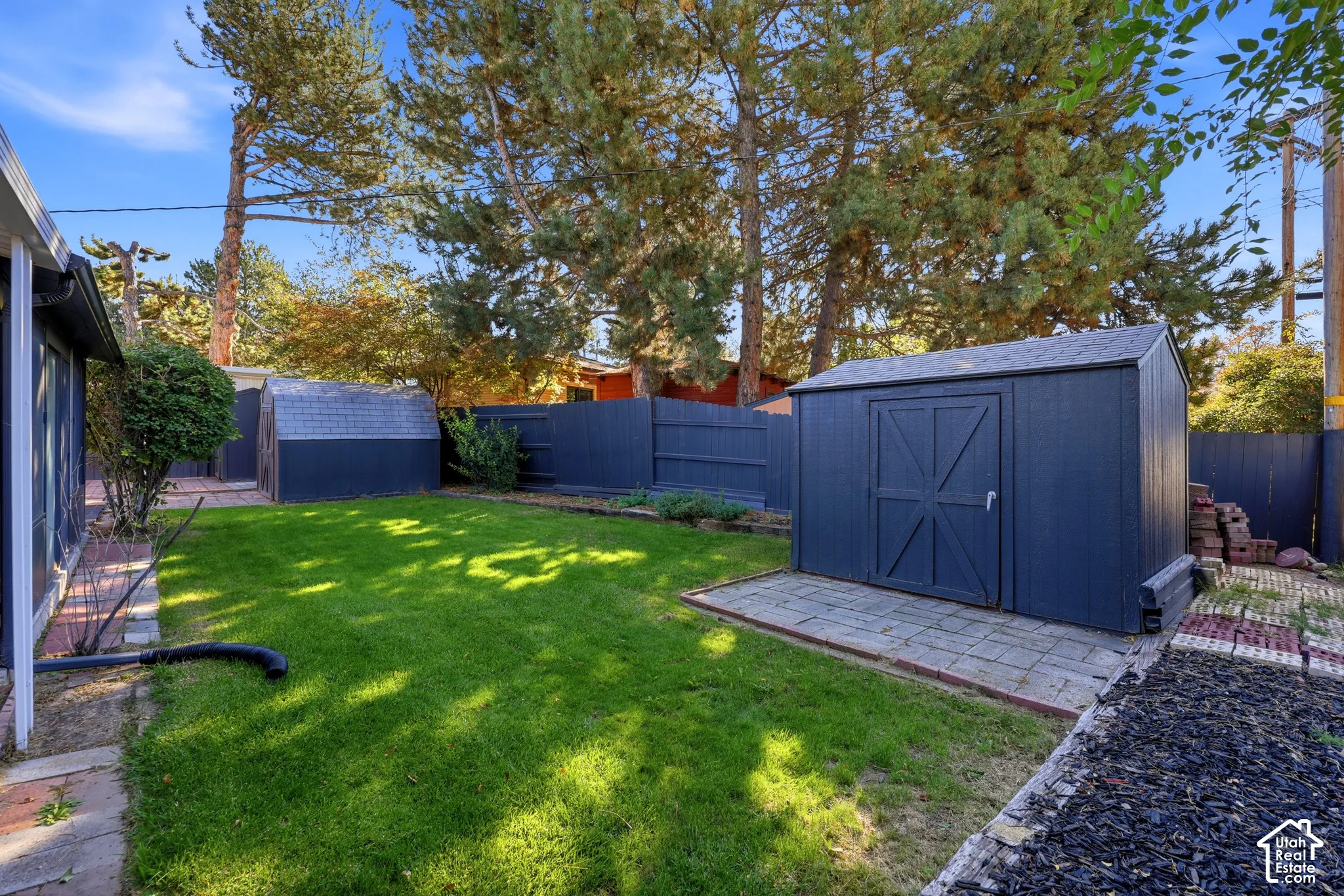 Manicured lawn with a detached storage shed, privacy fencing, and mature trees