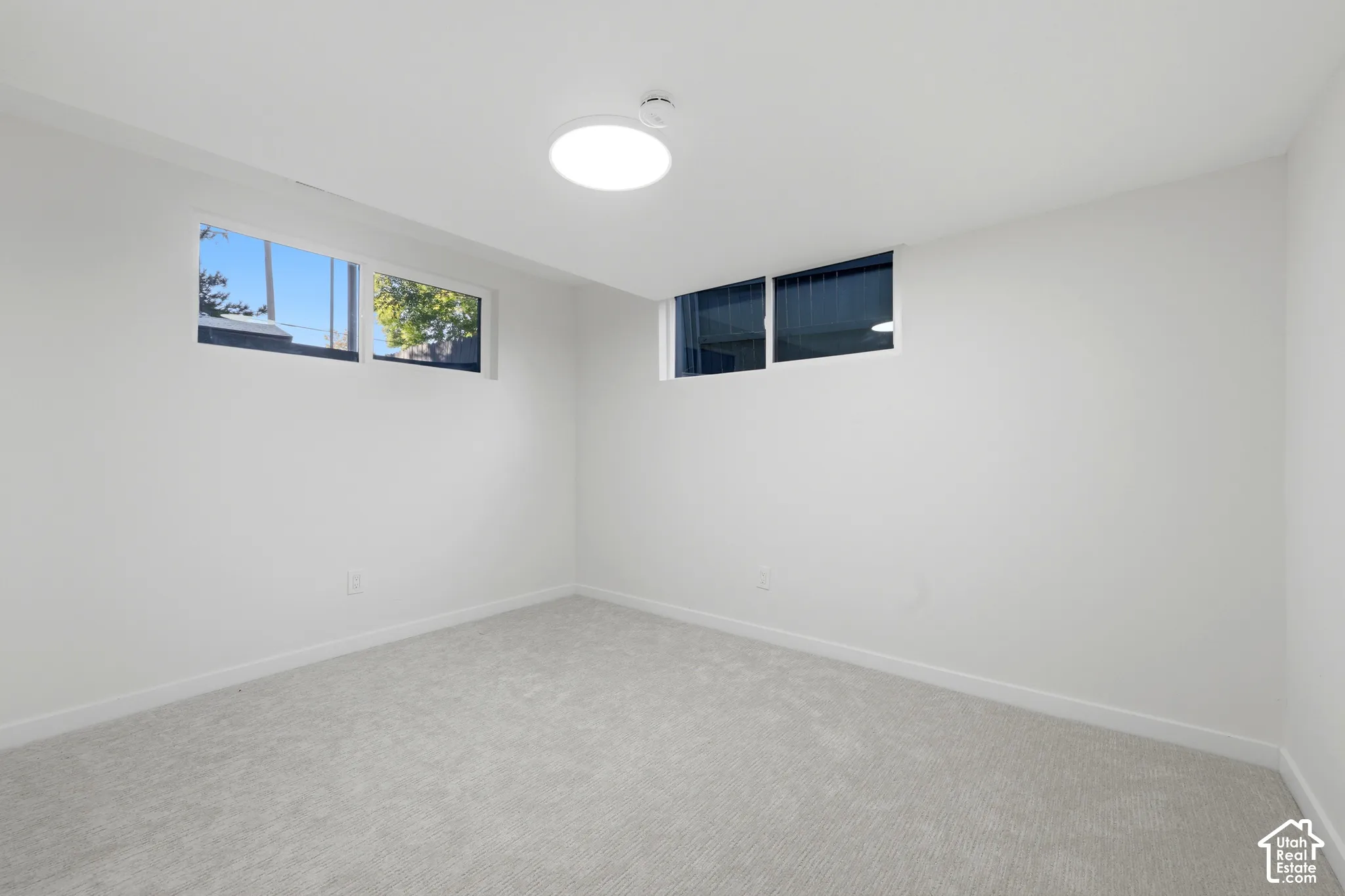 Neutral-toned carpeting paired with white walls, featuring multiple horizontal windows and recessed lighting