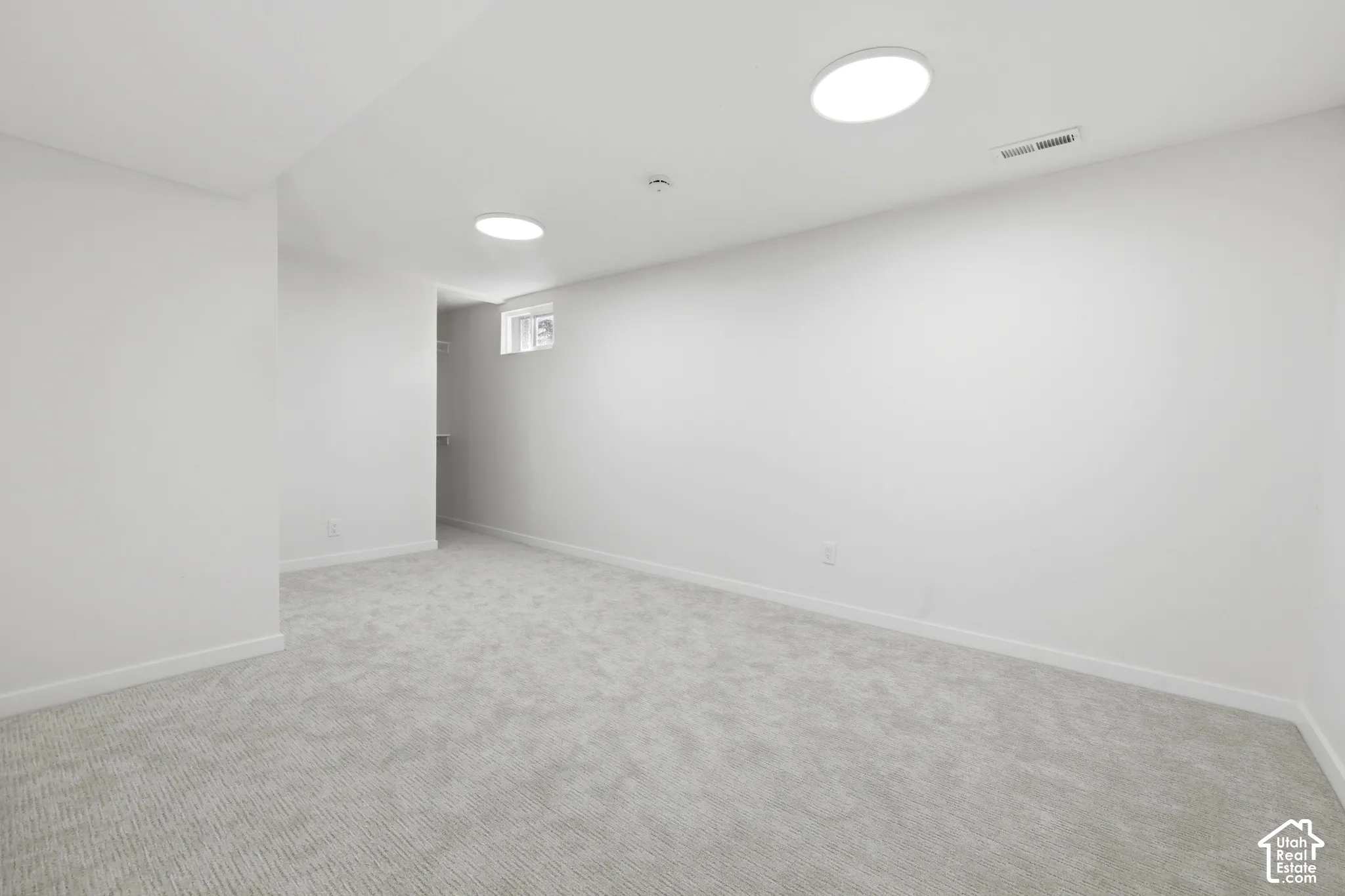 Light gray textured carpeting with white baseboards, recessed lighting, and a window