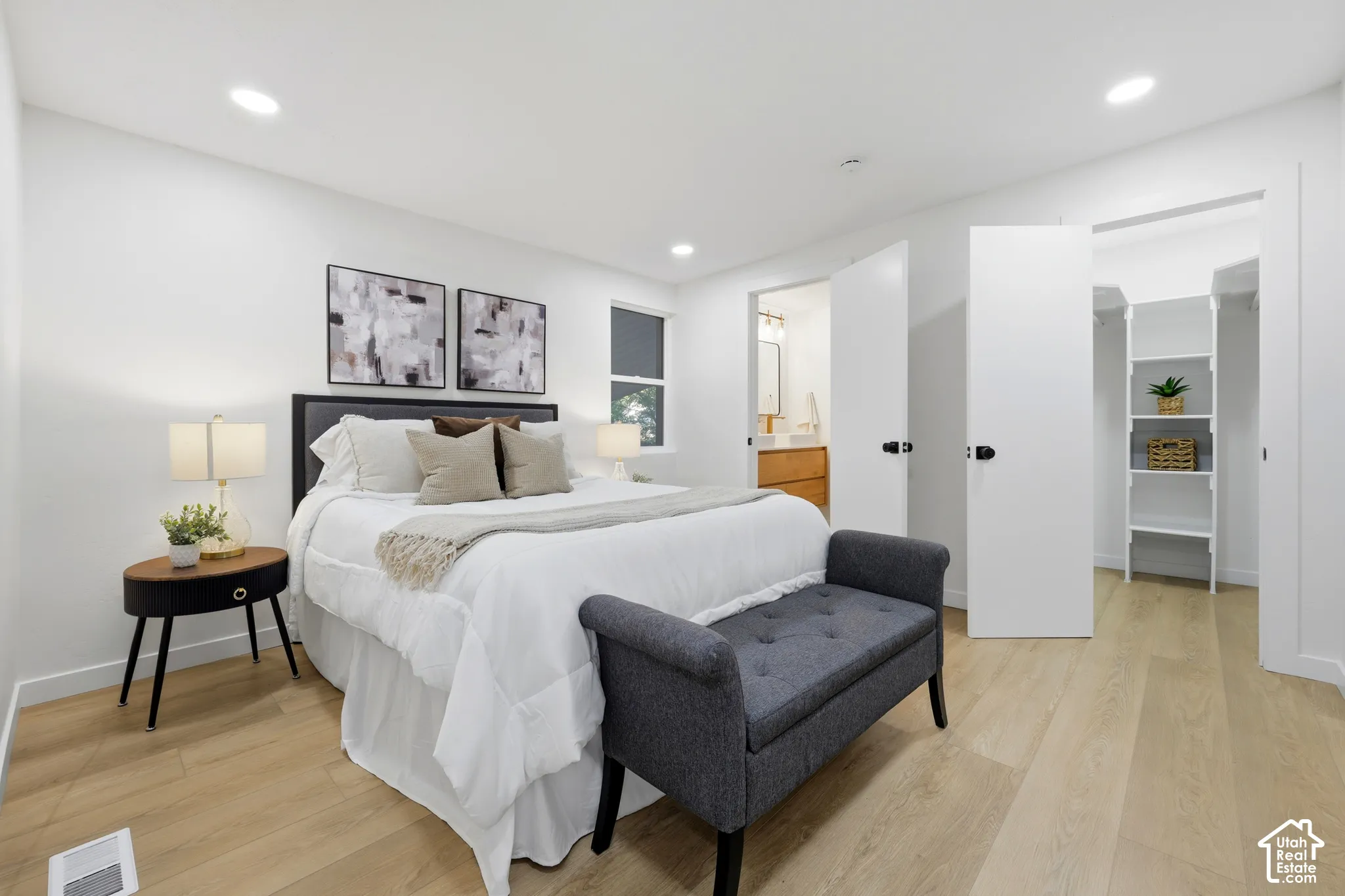 Recessed lighting, light wood-finish flooring, white walls, built-in closet shelving, and a window