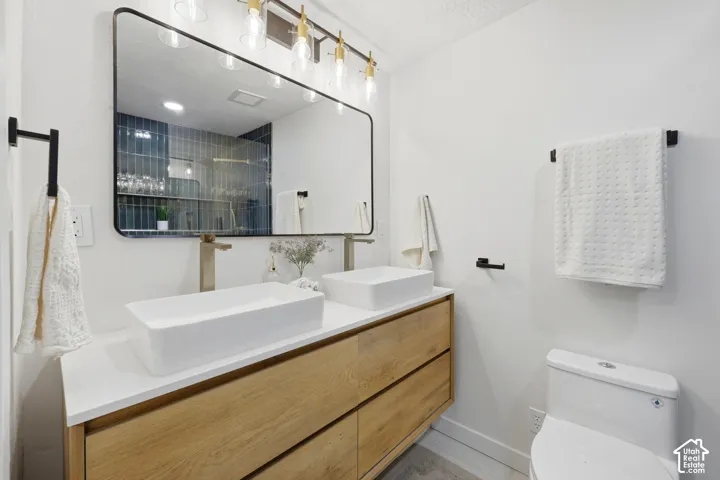 Dual rectangular vessel sinks, wood-finish vanity with drawer storage, wall-mounted brushed nickel faucets, and a large framed mirror with overhead vanity lighting