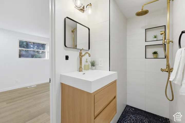 Floating wood-finish vanity with an integrated sink, black-framed rectangular mirror, and brass fixtures