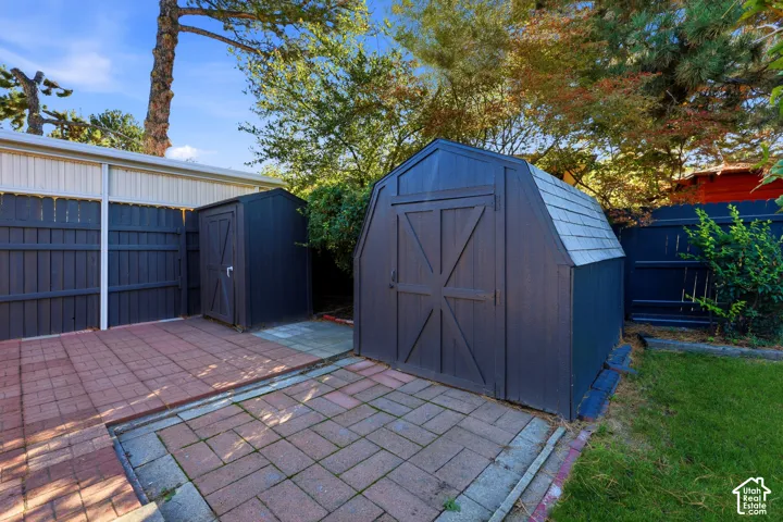 Paved patio area, two storage sheds, and a privacy fence