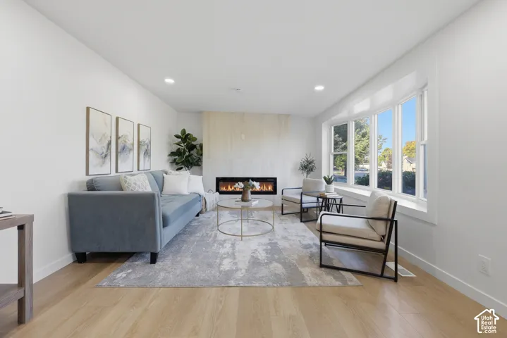 Recessed lighting, wood-finish flooring, a contemporary fireplace, and a bay window with white trim