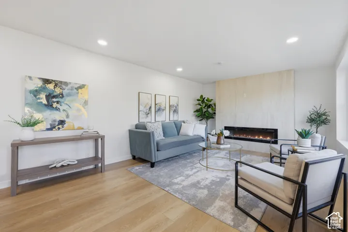 Recessed ceiling lighting, light wood-finish flooring, and a linear electric fireplace with a light-toned hearth