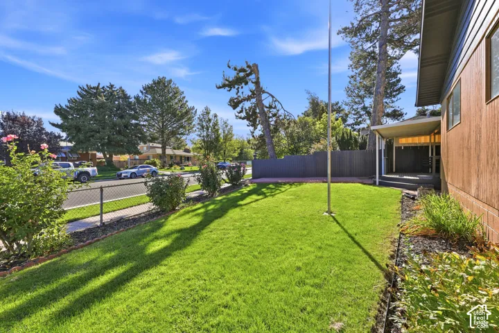 Expansive grassy lawn with established landscaping and a metal chain-link fence