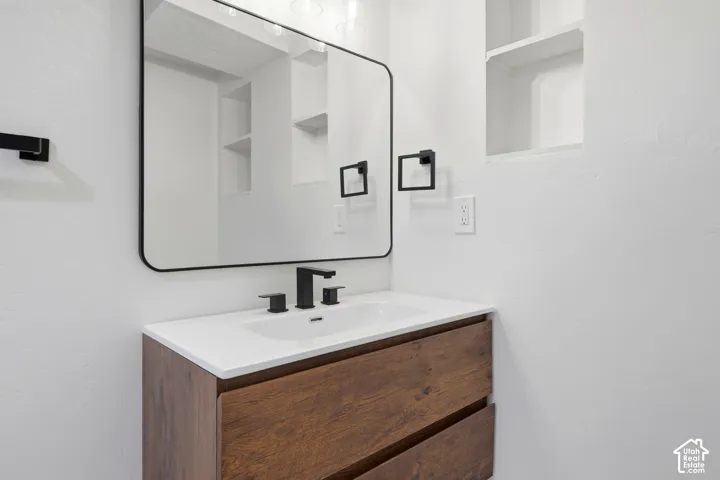 Wood-finish vanity with an integrated sink, matte black faucet, and a rectangular framed mirror