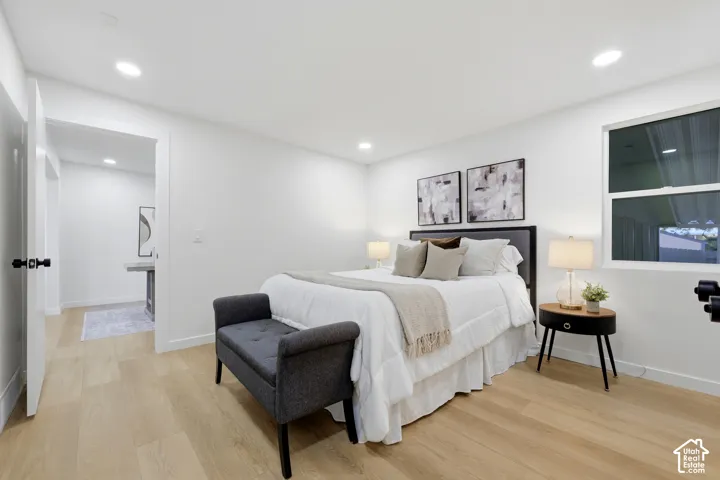 Recessed lighting, wood-finish flooring, white walls, and a window with dark framing