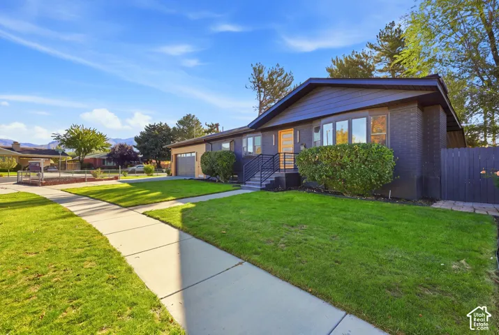 Exterior featuring dark brick facade, light wood-finish front door, front yard with green lawn, and an attached garage