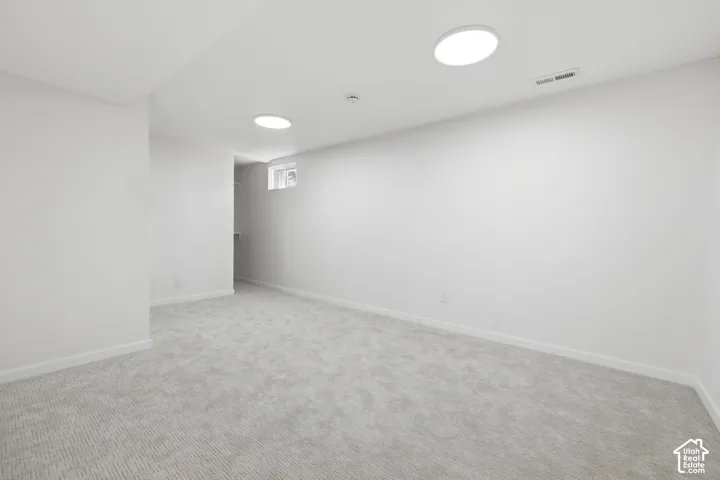 Light gray textured carpeting with white baseboards, recessed lighting, and a window