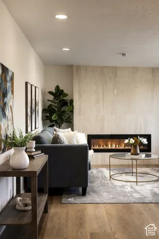 Recessed ceiling lighting, wood-finish flooring, and a linear fireplace with a stone-clad wall