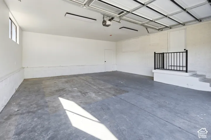 Spacious garage with concrete flooring, overhead lighting, and an automatic garage door opener