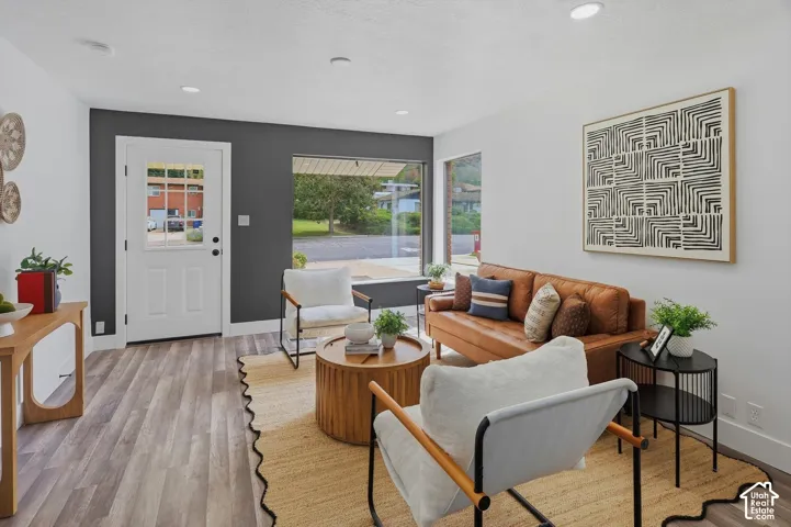 Wood-finish flooring, recessed lighting, white interior door with glass panes, large picture window, and accent wall