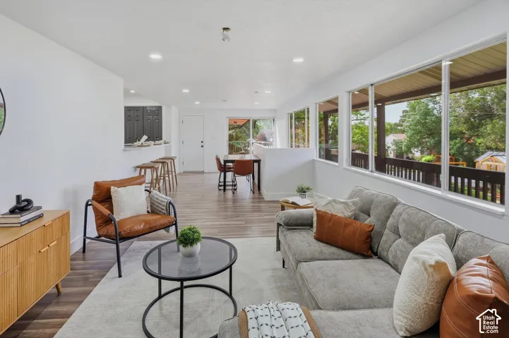 Open-concept living area with wood-finish flooring, white walls, and recessed lighting