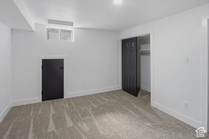 White painted walls, neutral carpet flooring, recessed ceiling lighting, a built-in closet with sliding doors, and a small built-in door
